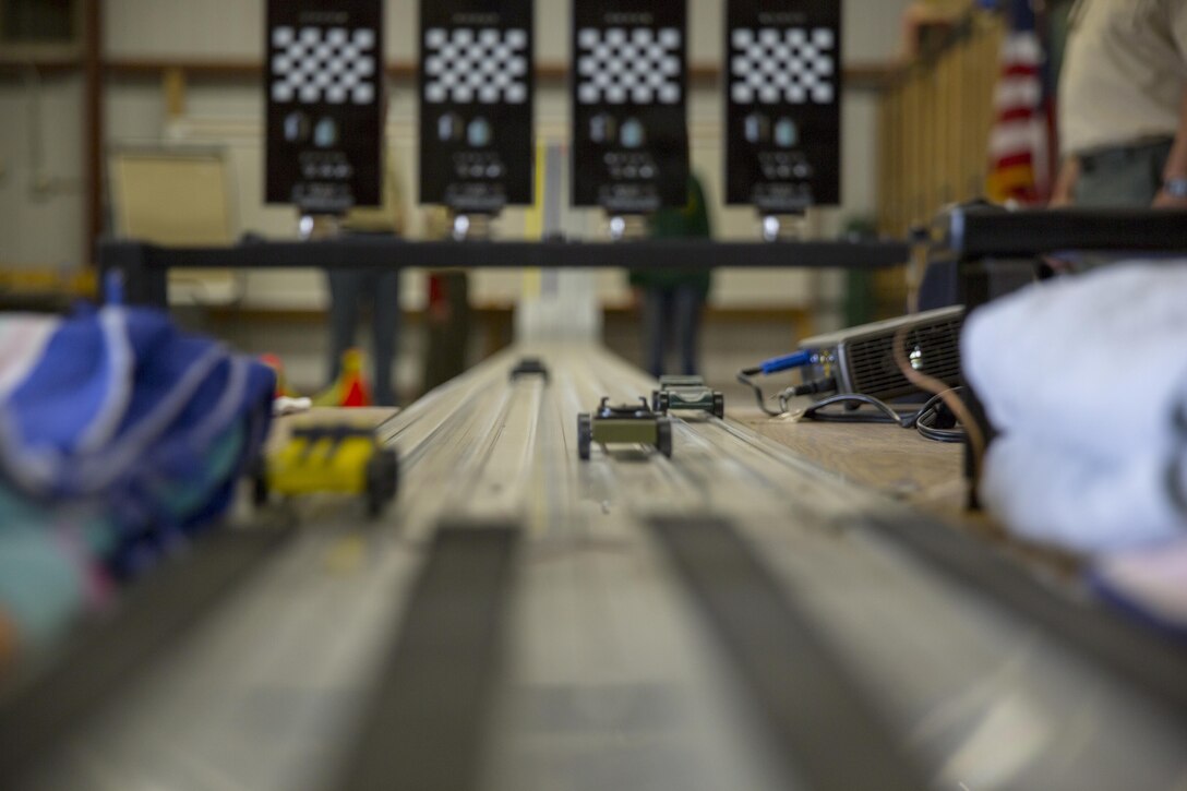Wooden racecars made by Cub Scout Pack 78 speed past the finish line during the annual Pinewood Derby at the Armed Services YMCA, Jan. 23, 2016. (Official Marine Corps photo by Lance Cpl. Levi Schultz/Released)