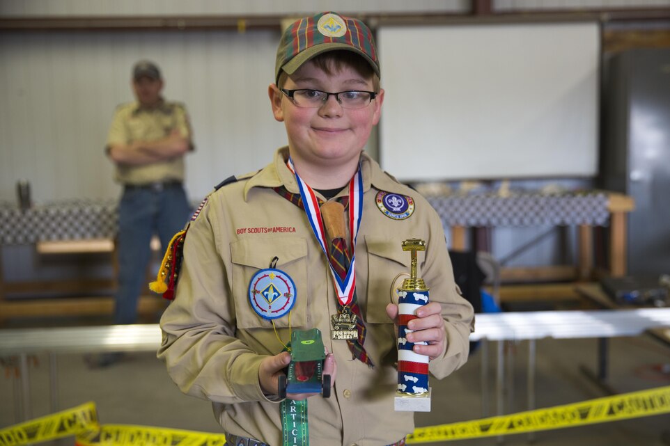 Roman Wylie, 10, son of Col. Jay Wylie, director, G-4 Installation and Logistics, displays his racecar, the Gator, and his first place trophy during the annual Cub Scout Pinewood Derby at the Armed Services YMCA aboard the Combat Center, Jan. 23, 2016. (Official Marine Corps photo by Lance Cpl. Levi Schultz/Released)