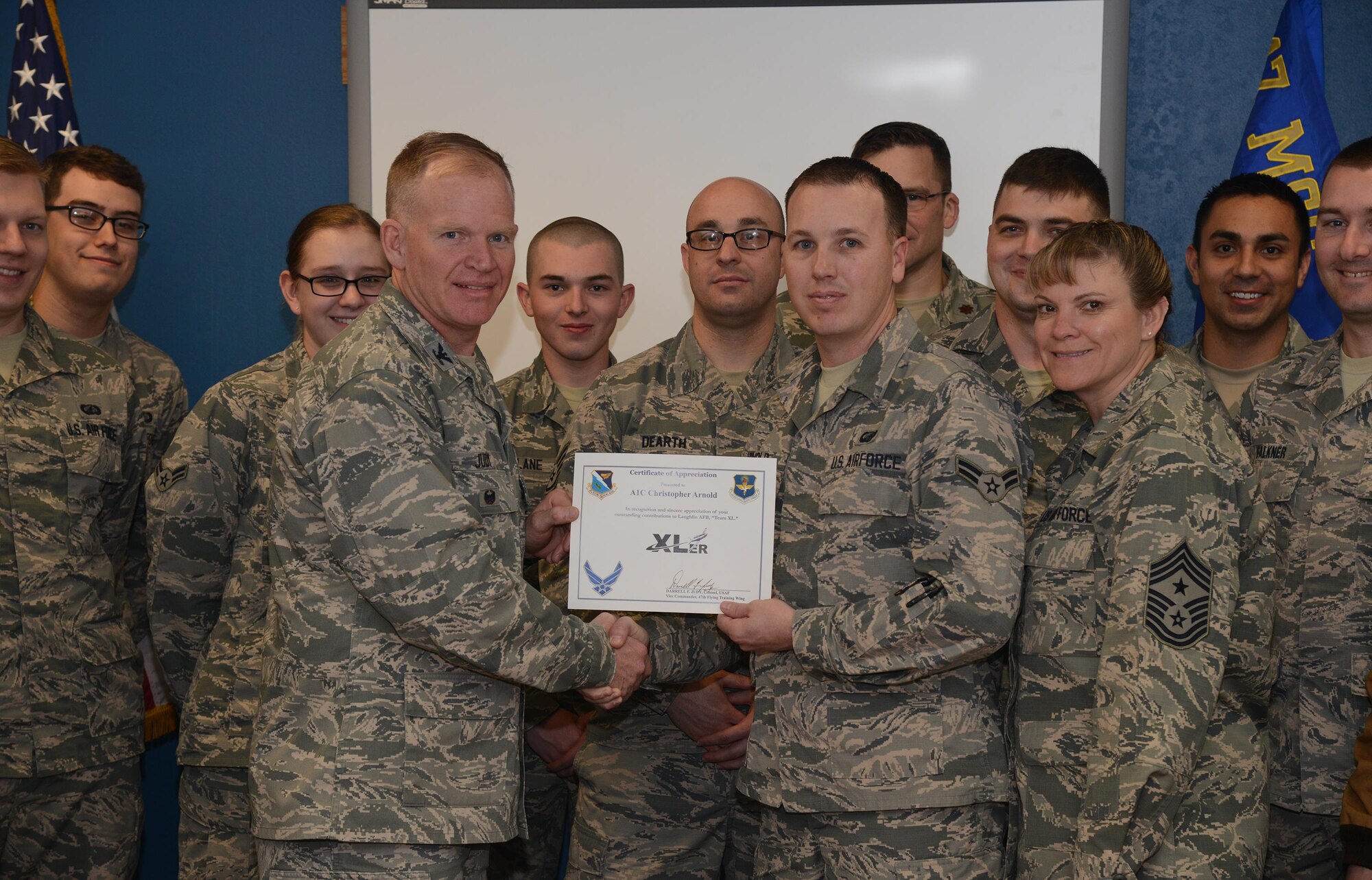 Airman 1st Class Christopher Arnold, center, 47th Contracting Flight contract specialist, accepts the “XLer of the Week” award from Col. Darrell Judy, left, 47th Flying Training Wing vice commander, and Chief Master Sgt. Teresa Clapper, right, 47th FTW command chief, here, Jan. 27, 2016. The XLer is a weekly award chosen by wing leadership and is presented to those who consistently make outstanding contributions to their unit and Laughlin. (U.S. Air Force photo by Airman 1st Class Brandon May)
