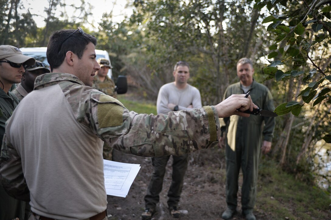 Air Force Staff Sgt. Brian Alfano, foreground, shows airmen the difference between safe and poisonous plant life during a combat and water survival training course on Homestead Air Reserve Base, Fla., Jan. 20, 2016. Alfano is a survival, evasion, resistance, and escape instructor assigned to the 103rd Rescue Squadron; the airmen are assigned to the 101st Rescue Squadron. During the training, aircrew members gained refresher training on using their emergency radios, moving tactically through difficult terrain, how to build shelters, ways to build fires, and evading the enemy. New York Air National Guard photo by Staff Sgt. Christopher S. Muncy