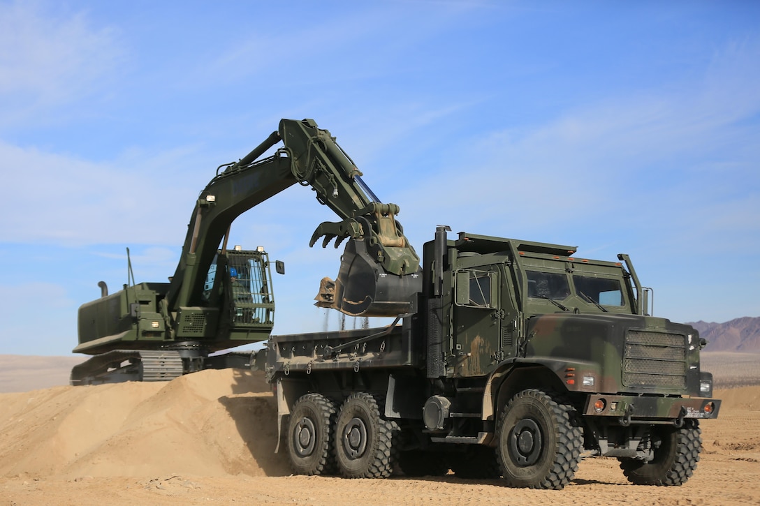 Staff Sgt. John Vasquez, heavy equipment operations chief, Marine Wing Support Squadron 374, scoops sand into a Medium Tactical Vehicle Replacement with a John Deere 250 GR Hydraulic Excavator near the Strategic Expeditionary Landing Field, Jan. 22, 2016. This is the first time MWSS-374 is using this excavator aboard the Combat Center and it is capable of utilizing interchangeable attachments to fulfill critical engineering missions. (Official Marine Corps Photo by Cpl. Julio McGraw/Released)