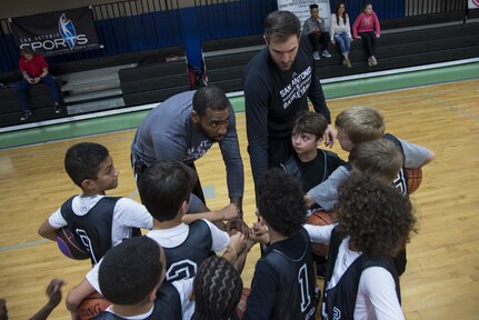Children from the Joint Base San Antonio-Randolph Youth Center huddle up with Rasual Butler, San Antonio Spurs forward, during a basketball skills camp Jan. 19, 2016 at the JBSA-Randolph Rambler Fitness Center. The camp is part of the Silver and Black Give Back program hosted by the San Antonio Spurs, offering young people age 5-16 an opportunity to play basketball and improve their athletic skills while learning teamwork, cooperation and discipline in a positive and safe environment. (U.S. Air Force Photo by Airman 1st Class Stormy Archer/Released)