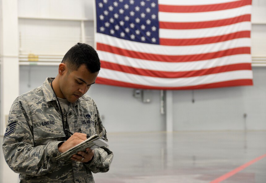 Tech. Sgt. Rafael Linero, 2nd Maintenance Group loading standardization crew member, makes notes while evaluating the weapons load finals at Barksdale Air Force Base, La., Jan. 22, 2016. The competition was based on a point system, each team began with 1,000 points and then were scored on dress and appearance, a B-52 Stratofortress weapons system and air munitions test, equipment inspection, and weapons loading technical operations. (U.S. Air Force photo/Senior Airman Amanda Morris)