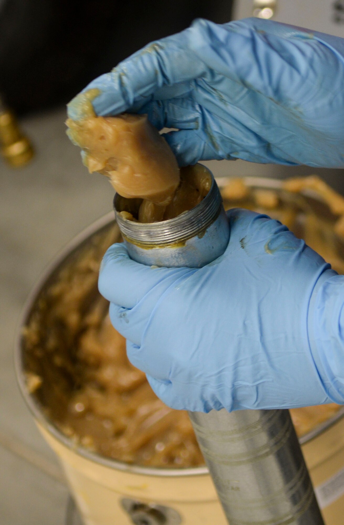 A weapons load crew team member from the 96th Aircraft Maintenance Unit loads a grease gun before participating in the weapons load finals at Barksdale Air Force Base, La., Jan. 21, 2016. Crew members used the grease guns when connecting the pylon package to the aircraft. (U.S. Air Force photo/Senior Airman Amanda Morris)