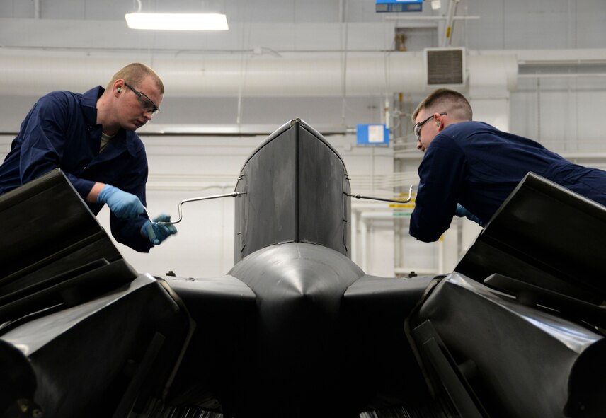 Weapons load crew team members from the 96th Aircraft Maintenance Unit open access panels to prep a pylon during the weapons load finals at Barksdale Air Force Base, La., Jan. 21, 2016. The Airmen loaded a munition onto the pylon during their competition performance. (U.S. Air Force photo/Senior Airman Amanda Morris)