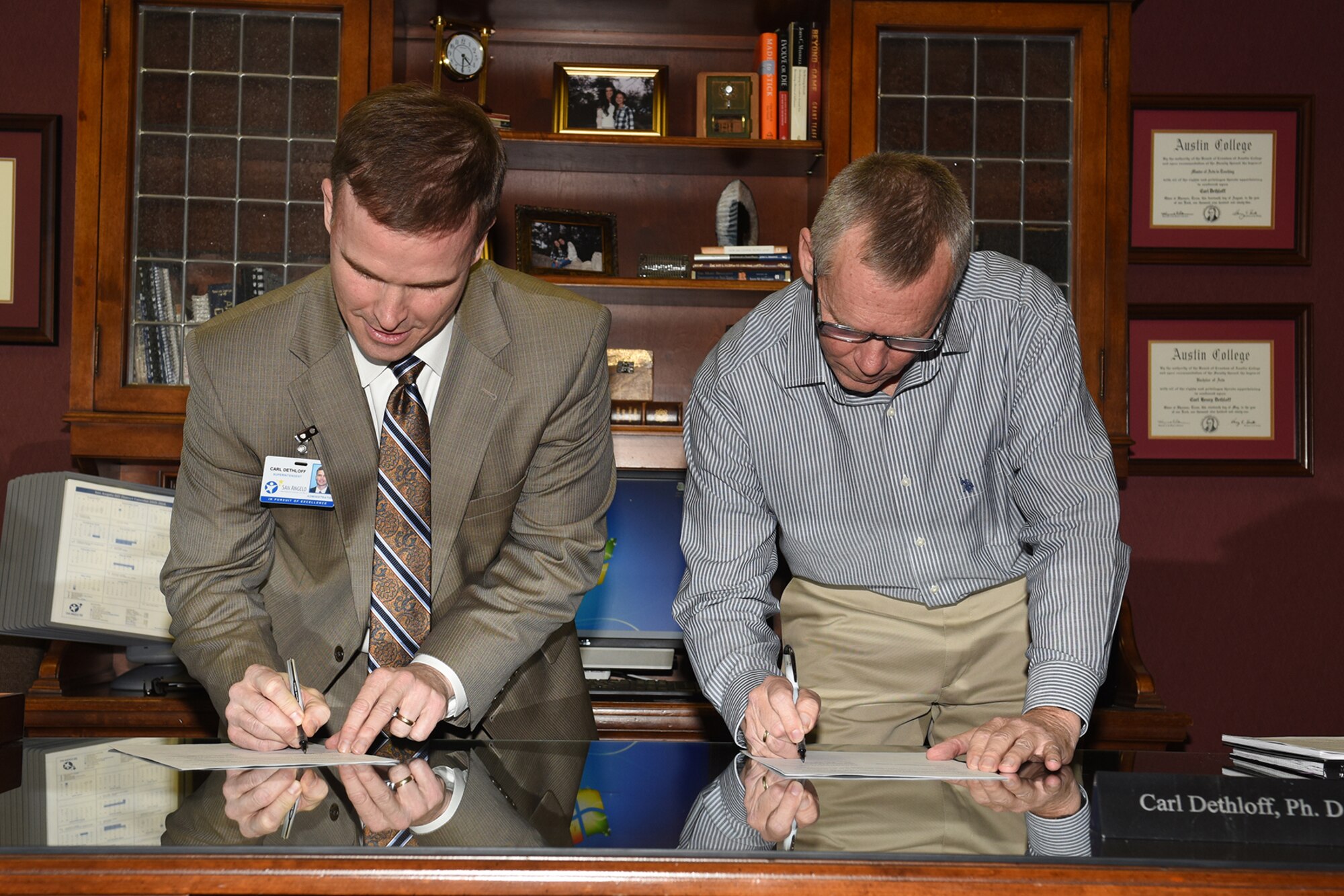 Dr. Carl Dethloff, San Angelo Independent School District superintendent, and Thomas A. Baker Jr., 17th Force Support Squadron deputy director, sign a Memorandum of Understanding for the partnership on student sponsorship program Help a New Kid Succeed at the SAISD administrative building, San Angelo, Texas, Jan. 25, 2016. HANKS is a program designed for kindergarten through 9th grade students to be sponsors for incoming new students both military and non-military affiliated. (U.S. Air Force photo by Staff Sgt. Laura R. McFarlane/Released)