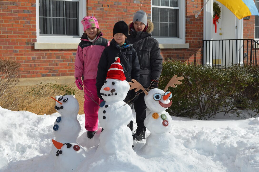 Kaitlyn, 8, Victor, 9, and Igor, 10, pose with their snow creations on Monday, as they enjoy the day off from school.