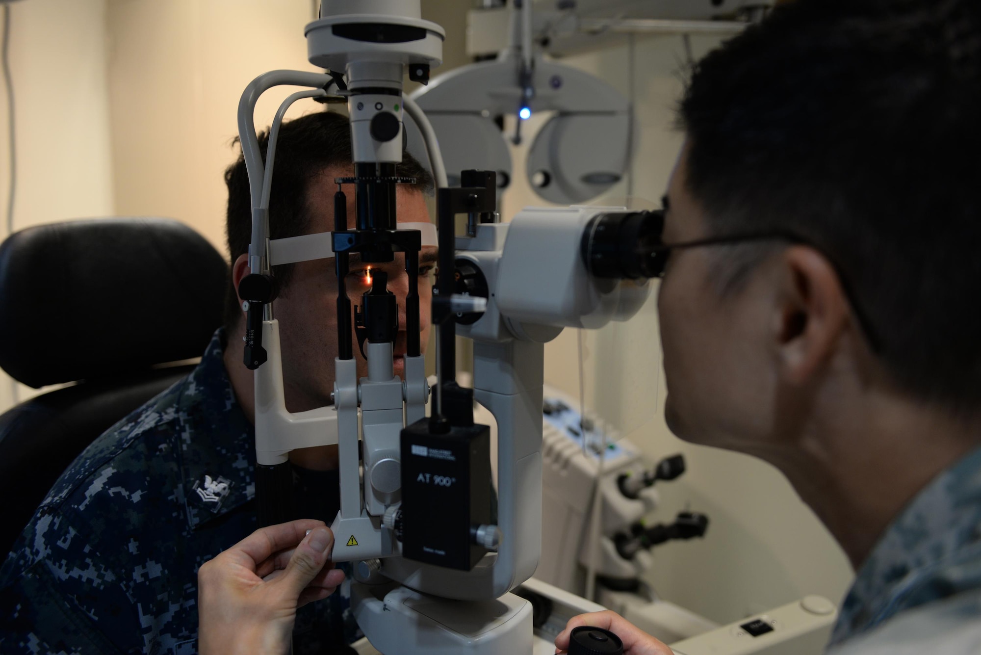 Maj. John Kim, 36th Medical Operations Squadron chief of optometry services, inspects the eye of Petty Officer 2nd Class Chris Rumbaua, Fleet Air Forward Detachment Aircraft Intermediate Maintenance Department life support technician, Jan. 27, 2016, at Andersen Air Force Base, Guam. Kim used a slit lamp, which allows him to closely inspect the eyes by combining a movable light source and magnification. (U.S. Air Force Photo/Airman 1st Class Jacob Skovo)