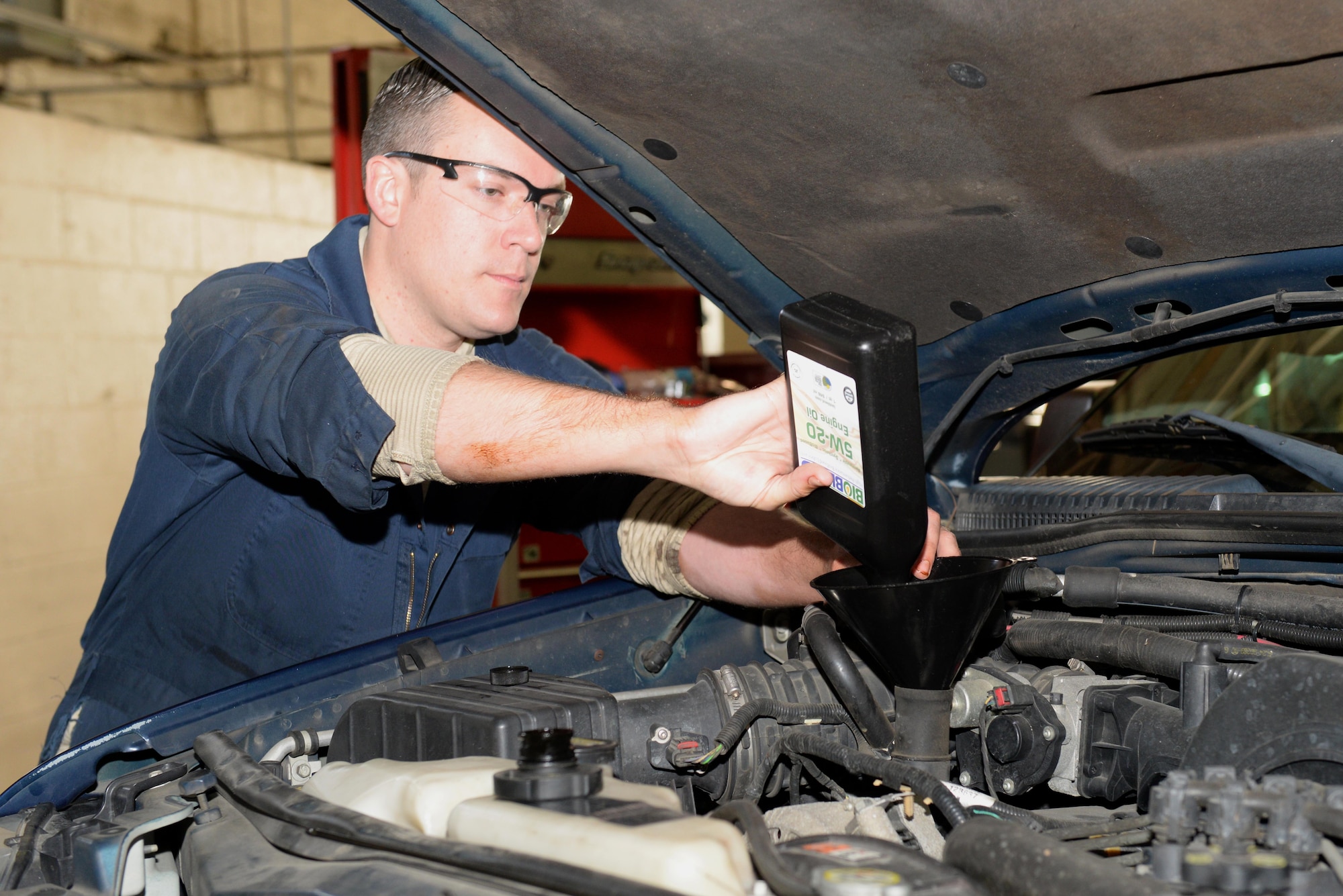 Senior Airman James Preston, 4th Logistics Readiness Squadron aircraft loader mechanic, pours biobased synthetic oil into a government owned vehicle, Jan. 26, 2016, at Seymour Johnson Air Force Base, North Carolina. Seymour Johnson AFB is the first of four bases to test the new biobased four cycle motor oil as part of a 12 to 18 month trial. (U.S. Air Force photo/Airman 1st Class Ashley Williamson)