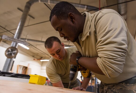 Senior Airman Jaylon Gordon, 366th Civil Engineer Squadron heating ventilation and air conditioning specialist, screws two boards together, Jan. 25, 2016, at Mountain Home Air Force Base, Idaho. The boards create part of the foundation forms used to hold concrete at the base of the building. (U.S. Air Force photo by Airman 1st Class Connor J. Marth/RELEASED)