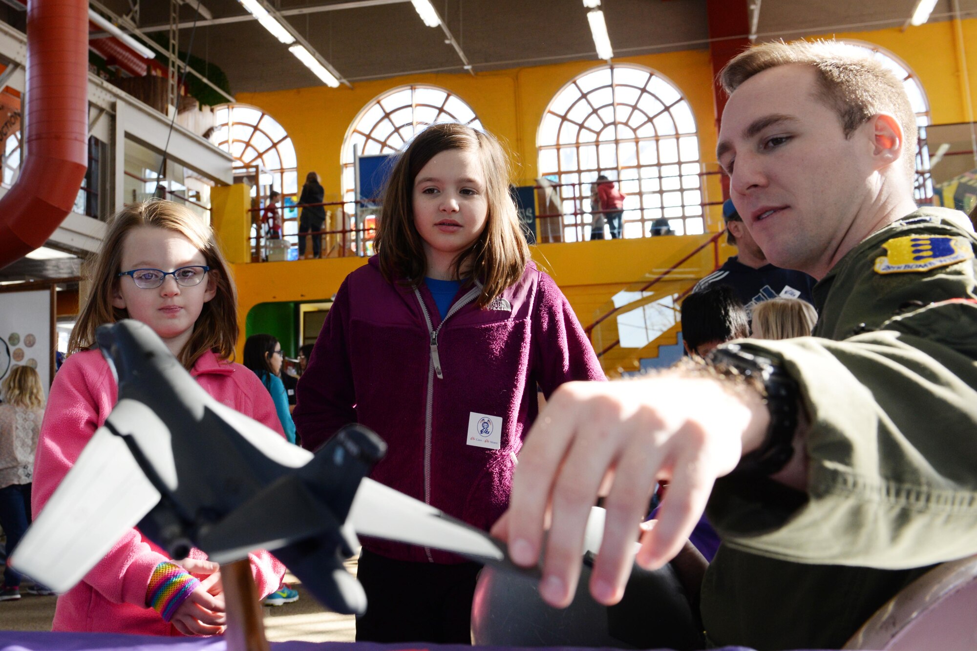 First Lt. Harold Engler, 34th Bomb Squadron weapon systems officer, describes the operations of a B-1 bomber to Claire and Madeline Brakke during the 2016 Aviation Day at the Discovery Center in Pierre, S.D., Jan. 27, 2016. Five aircrew members from Ellsworth Air Force Base, S.D., traveled to Pierre to participate in the event, making it a memorable experience for children from across the state. (U.S. Air Force photo by Senior Airman Rebecca Imwalle/Released)