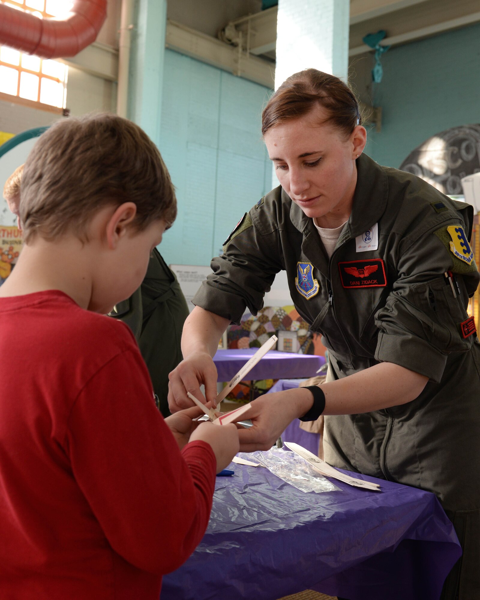 Eli Goldammer builds a toy glider with 1st Lt. Danielle Zidack, 34th Bomb Squadron weapon systems officer, during the 2016 Aviation Day at the Discovery Center in Pierre, S.D., Jan. 27, 2016. In addition to Airmen from Ellsworth Air Force Base, S.D., members of the Civil Air Patrol, Great Lakes Airline and Mustang Aviation also participated in the event, teaching children about aviation. (U.S. Air Force photo by Senior Airman Rebecca Imwalle/Released)
