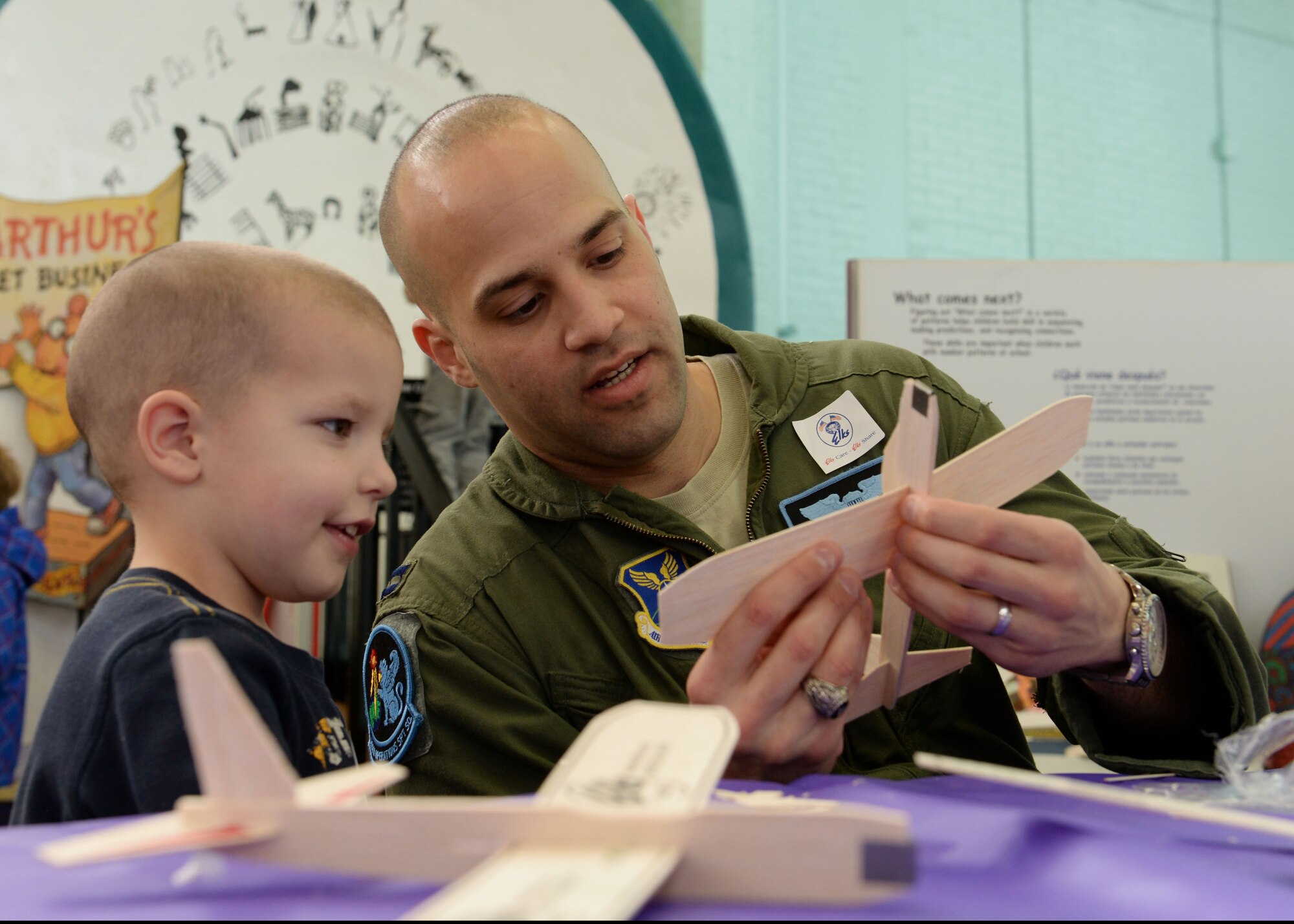 Capt. Hansel Rabbell, 28th Operations Support Squadron chief of wing scheduling, explains the a toy glider to Tonda Winifred-Morris during the 2016 Aviation Day at the Discovery Center in Pierre, S.D., Jan. 27, 2016. This was the third annual event of its kind, and is one of several youth events organized by the Elks Lodge. (U.S. Air Force photo by Senior Airman Rebecca Imwalle/Released)
