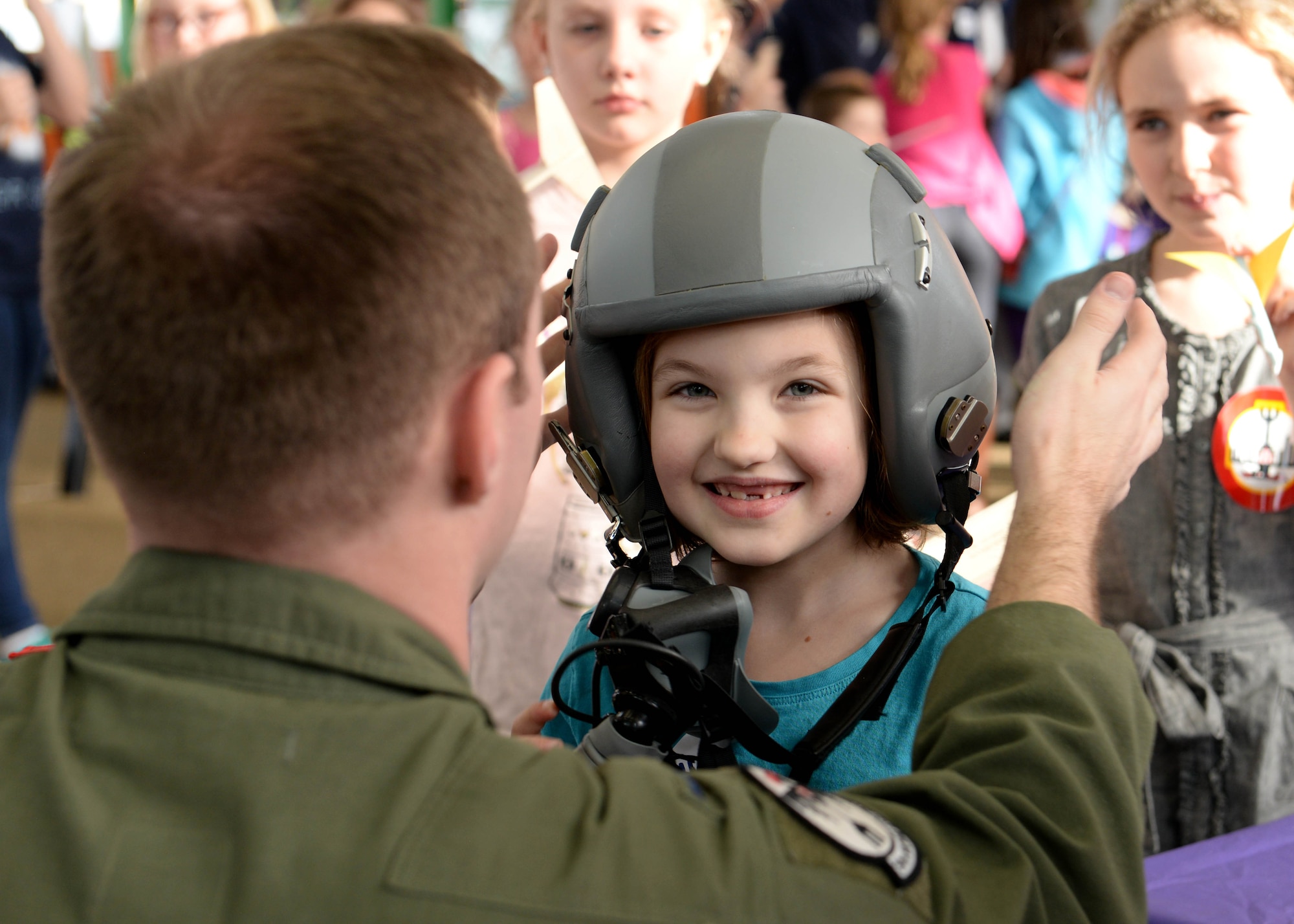 First Lt. Harold Engler, 34th Bomb Squadron weapon systems officer, places a helmet on Alexia Winifred-Morris during the 2016 Aviation Day at the Discovery Center in Pierre, S.D., Jan. 27, 2016. Engler and four other aircrew members participated in the event, bringing helmets, flight suits and harnesses for the children to try on while learning about their job. (U.S. Air Force photo by Senior Airman Rebecca Imwalle/Released)