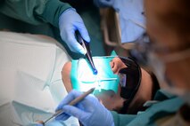 Jessica Arroyo, 22nd Aerospace Medicine Squadron dental assistant, uses a Valvo LED curing light to a patient’s teeth, Jan. 27, 2016, at McConnell Air Force Base, Kan.  A curing light is used to quickly harden compsite filling material used by a dentist when filling in cavities. (U.S. Air Force photo/Senior Airman Colby L. Hardin)
