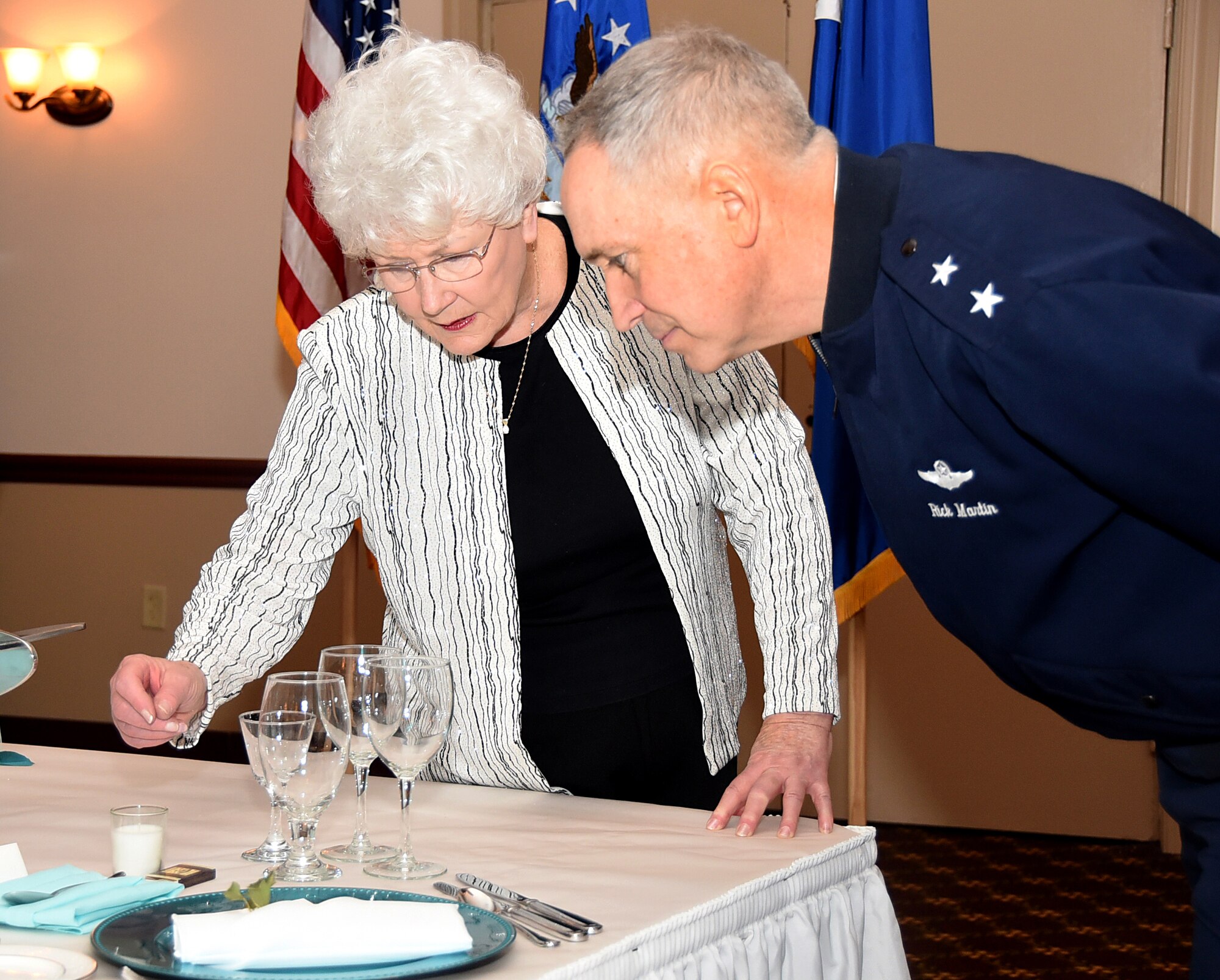 160115-F-CK424-035 Maggie Bonner, the chief of protocol for the Air Force Education and Training Center at Randolph Air Force Base, explains to Maj. Gen. Frederick Martin, the U.S. Air Force Expeditionary Center commander, the significance of each item on the table prior to a Heritage Dinner on Jan. 15, 2016, at Joint Base McGuire-Dix-Lakehurst, New Jersey. The Heritage Dinner was derived from the Corona Heraldic Dinner, which originated as a meeting of all Air Force major commanders lead by then Chief of Staff of the Air Force, Gen. Curtis E. LeMay. (U.S. Air Force photo/Tech. Sgt. Jamie Powell)