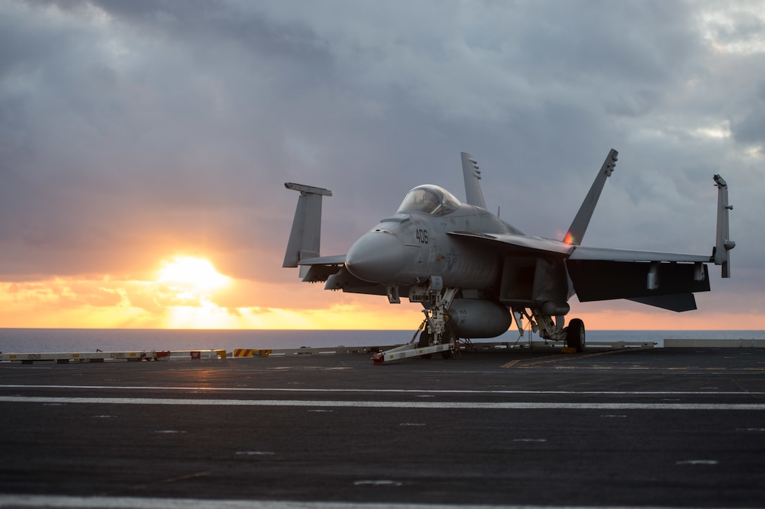 The sun rises behind an F/A18E Super Hornet assigned to the Vigilantes of Strike Fighter Squadron 151 on the flight deck of the USS John C. Stennis in the Pacific Ocean, Jan. 28, 2016. Providing a combat-ready force to protect collective maritime interests, Stennis is operating as part of the Great Green Fleet on a regularly scheduled Western Pacific deployment. U.S. Navy photo by Seaman Cole C. Pielop