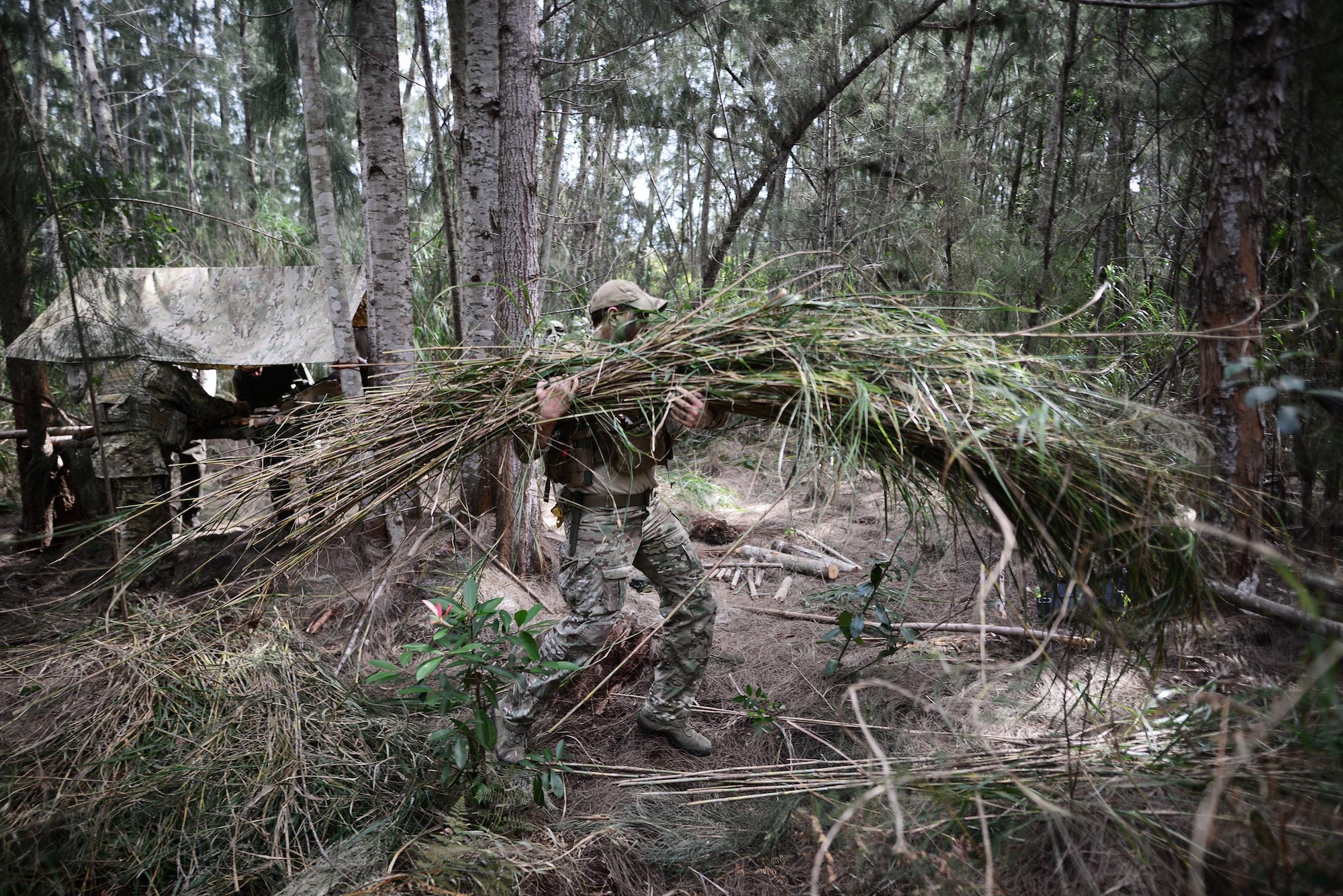 Senior Airman Ian Kuhn, a survival, evasion, resistance, and escape (SERE) instructor with the 103rd Rescue Squadron, demonstrates how to build a concealed shelter during a combat and water survival training course at Homestead Air Reserve Base, Fla., Jan. 20, 2016. During this training, aircrew members gained refresher training on using their emergency radios, tactical movements through difficult terrain, how to build shelters, ways to build fires and methods for evading the enemy. (U.S. Air National Guard/Staff Sgt. Christopher S. Muncy)