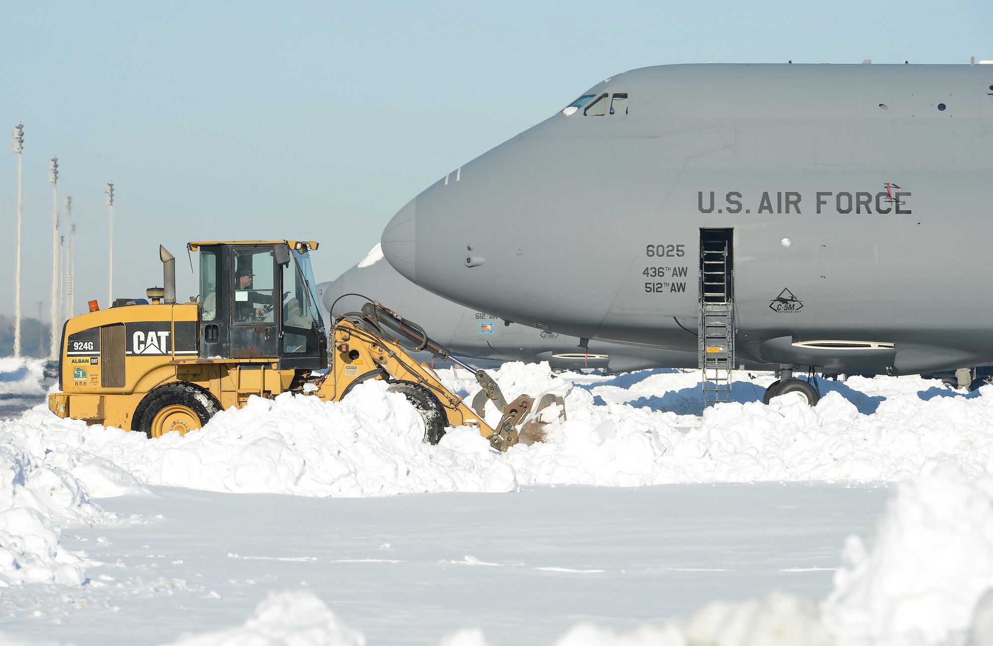 A Caterpillar front loader clears the Dover Air Force Base, Del., flightline near a C‐5M Super Galaxy airlift aircraft, assigned to the 436th Airlift Wing, during recovery operations Jan. 25, 2016, after Winter Storm Jonas. Heavy equipment cleared the open areas while hand shovels were used to clear the 22 inches of accumulated snow from around the aircraft. (U.S. Air Force photo/Greg L. Davis)