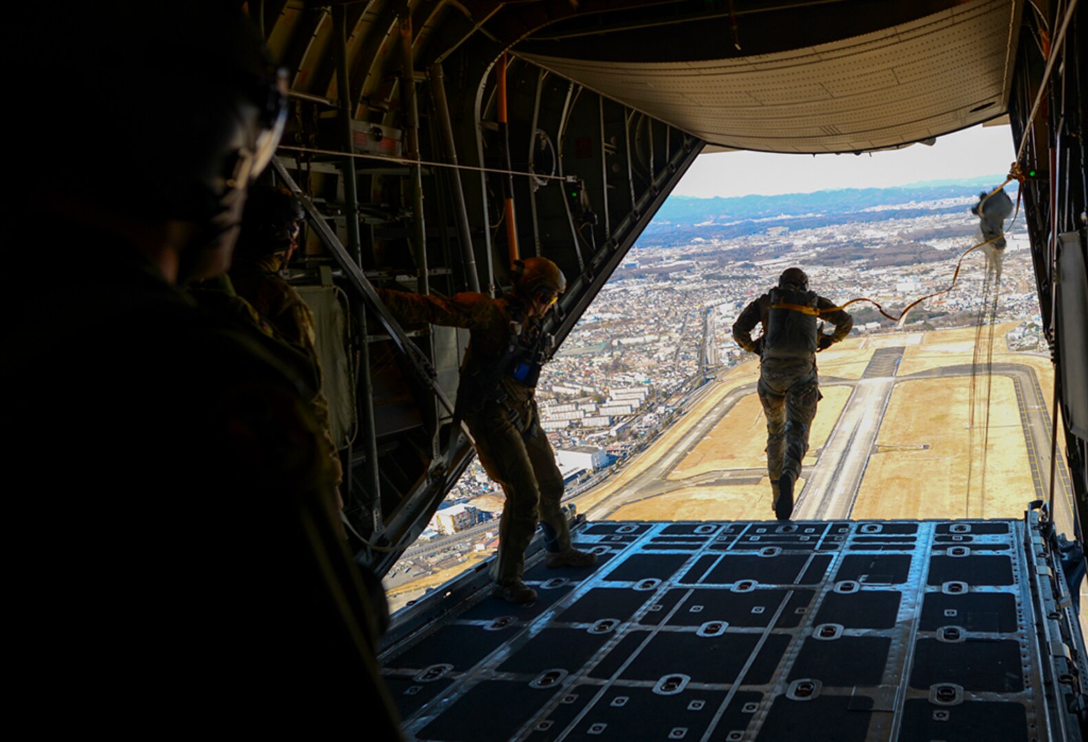 Senior Airman Andrew Fox, 36th Airlift Squadron instructor C-130 Hercules loadmaster, supervises a personnel drop over Yokota Air Base, Japan Jan. 25, 2016. Loadmasters are responsible for ensuring that aircraft cargo and passengers are transported safely and in a timely manner, which involves preparing rigging inside the aircraft and performing checks before and during the flight to ensure the safety of personnel and equipment. 