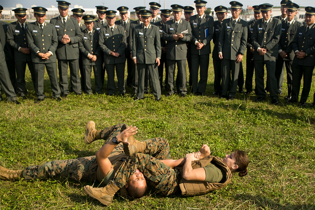 First Lt. Melissa Cooling demonstrates a Marine Corps Martial Arts Program arm bar to Japan Ground Self-Defense Force officer candidates on Camp Kinser, Okinawa, Japan, Jan. 15. Three hundred and sixty officer candidates visited Combat Logistics Regiment 35 to complete joint and combined operation requirements. The cadets watched Marine Corps Martial Art Program demonstrations, learned the capabilities of various machine guns the Marine Corps uses, and observed a static display of motor transportation vehicles. Cooling, from Southbury, Connecticut, is the current operations officer with CLR-35, 3rd Marine Logistics Group, III Marine Expeditionary Force. 