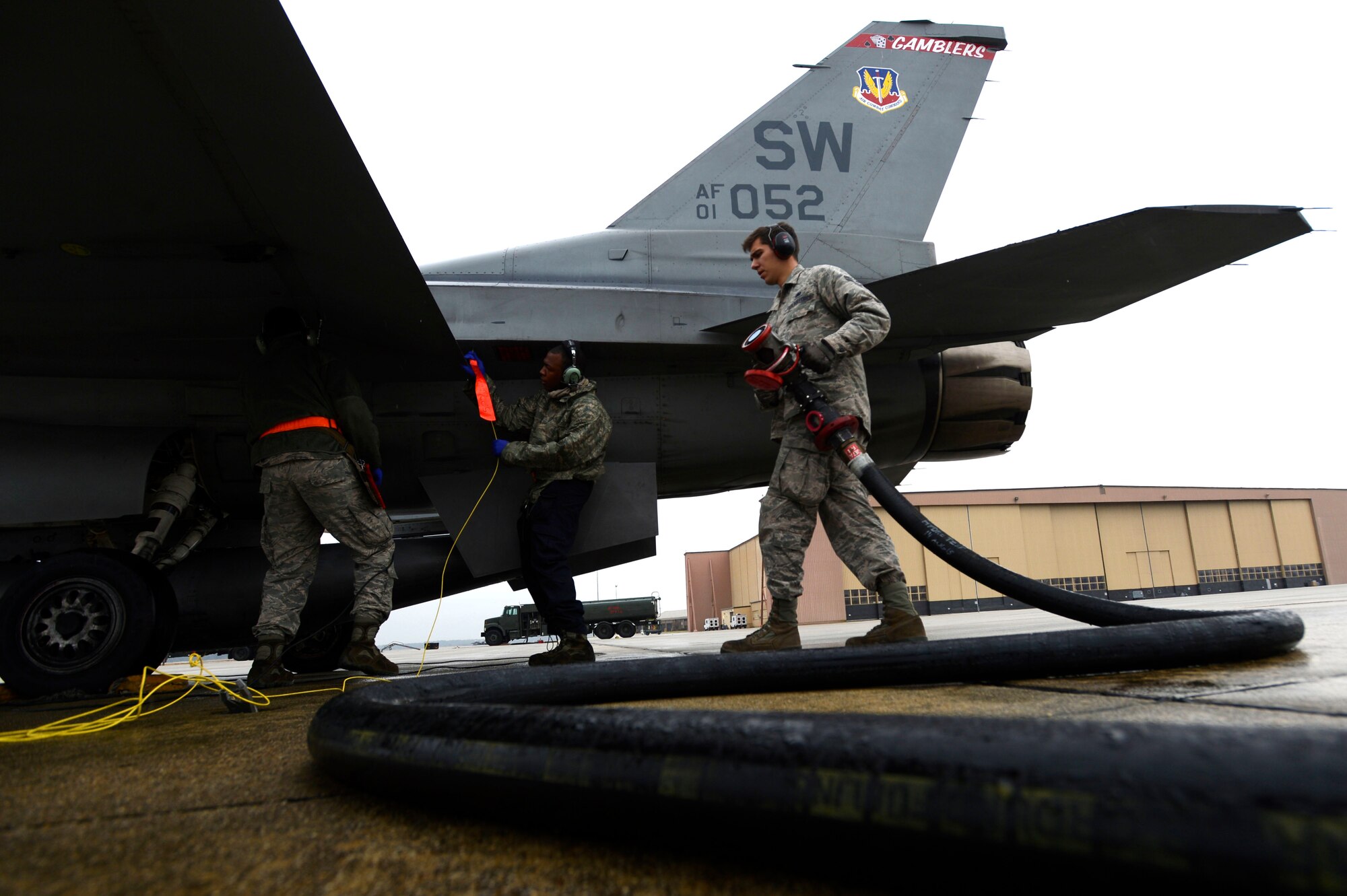 U.S. Air Force Airman 1st Class Keagan Arledge, 20th Logistics Readiness Squadron fuels apprentice, pulls a fuel hose during hot-pit refueling at Shaw Air Force Base, S.C., Jan. 28, 2016. The fuel hose is pulled from a nearby R-11 refueling truck that can carry up to 6,000 pounds of jet fuel. (U.S. Air Force photo by Senior Airman Jensen Stidham/Released)