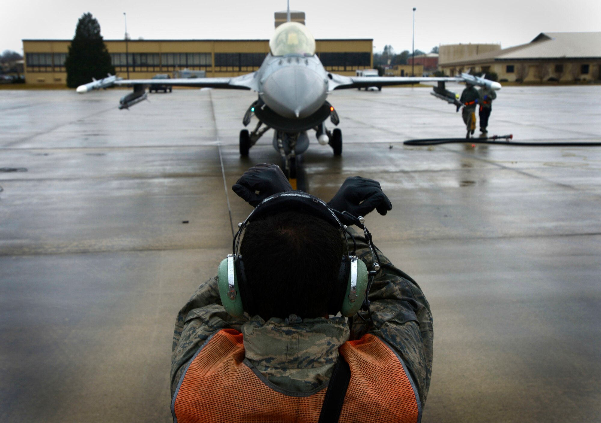 U.S. Air Force Senior Airman David Cano-Mejia, 20th Aircraft Maintenance Squadron tactical aircraft maintainer, signals an F-16CM Fighting Falcon to stop in preparation to be hot-pit refueled at Shaw Air Force Base, S.C., Jan. 28, 2016. Before entering the fueling station, Airmen conduct a cursory check to inspect the jet before connecting the fuel hose. (U.S. Air Force photo by Senior Airman Jensen Stidham/Released) 
