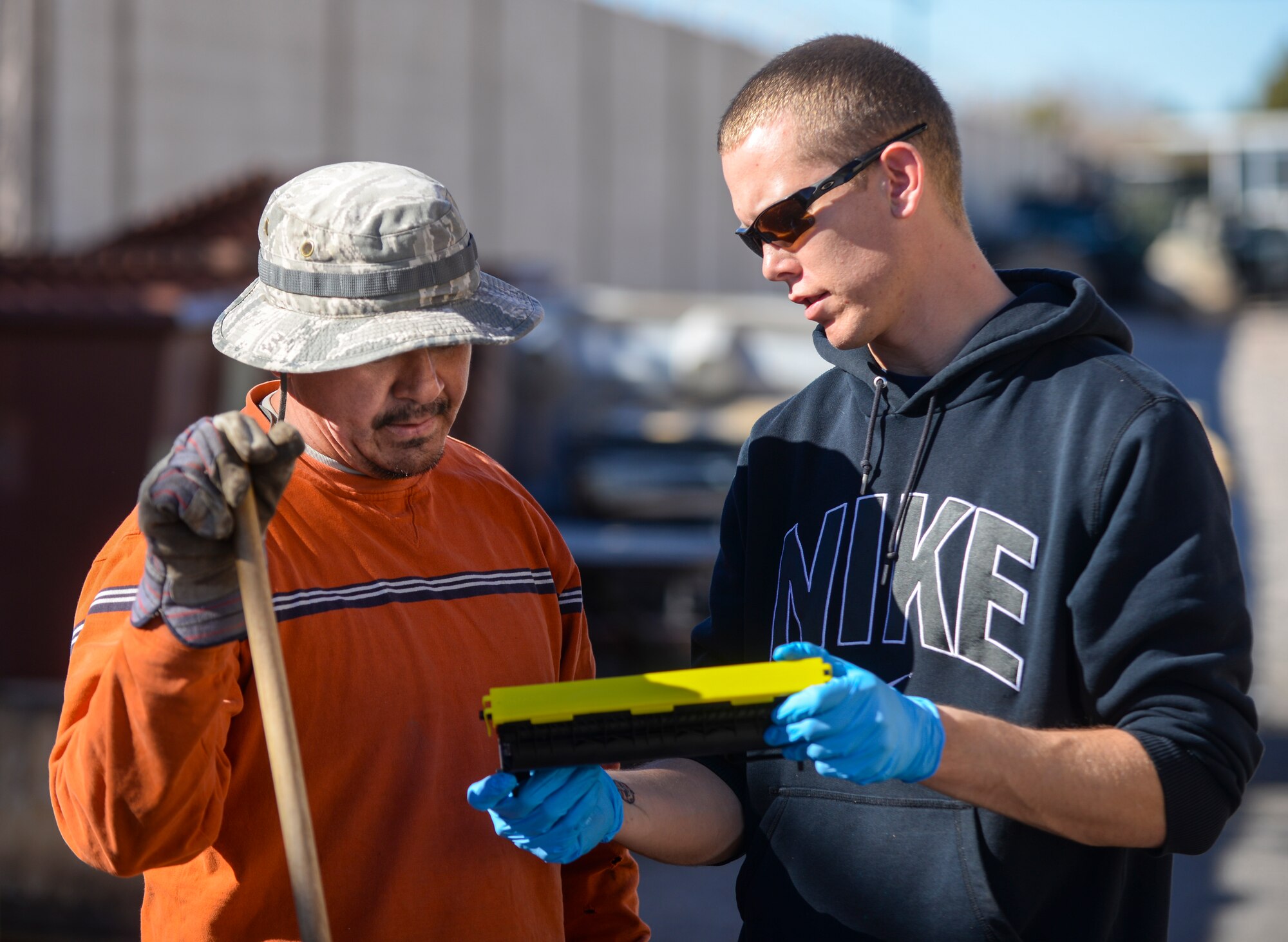 Gamy Manriquez (left), Nellis AFB Recycling Center recycling program manager, instructs where to put recycled goods to Airman 1st Class Douglas Wheeler (right), 823rd Maintenance Squadron HH-60 crew chief, during a volunteer event at the Recycling Center at Nellis Air Force Base, Nev., Jan. 26, 2016,. Volunteering is a passion for Wheeler and orchestrated the volunteer event at the Recycling Center for his squadron. (U.S. Air Force photo by Airman 1st Class Kevin Tanenbaum)