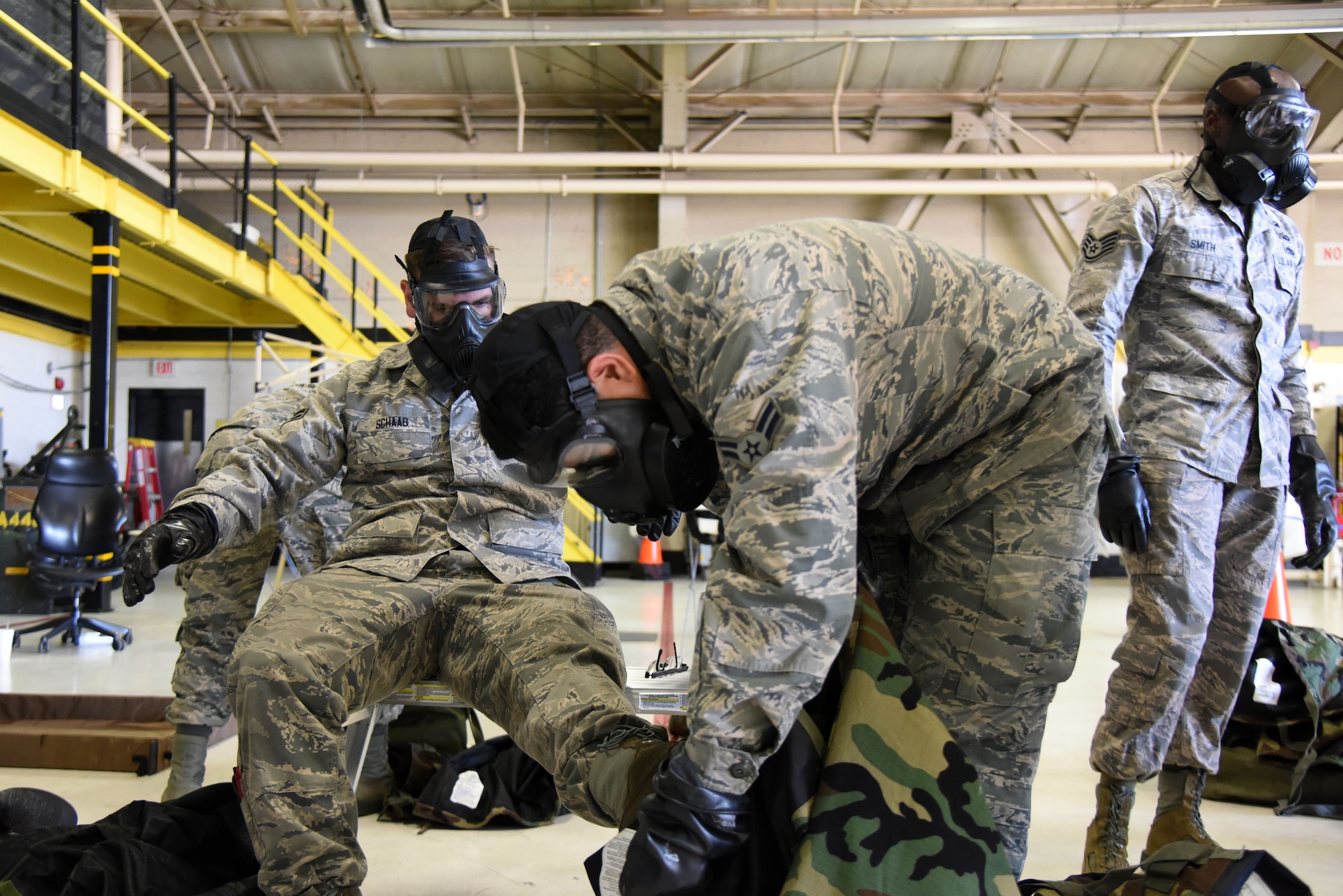 Airman 1st Class Elijah Afraid of Lightening, 4th Equipment Maintenance Squadron aircraft structural maintenance journeyman, removes mission oriented protective posture gear from Airman 1st Class Benjamin Schaab, 4th EMS aircraft structural maintenance journeyman, Jan. 29, 2016 at Seymour Johnson Air Force Base, North Carolina. As part of exercise Coronet Warrior 16-01, the Airmen demonstrated their ability to survive and operate in a chemical environment for wing inspection team members. (U.S. Air Force photo/Staff Sgt. Chuck Broadway)