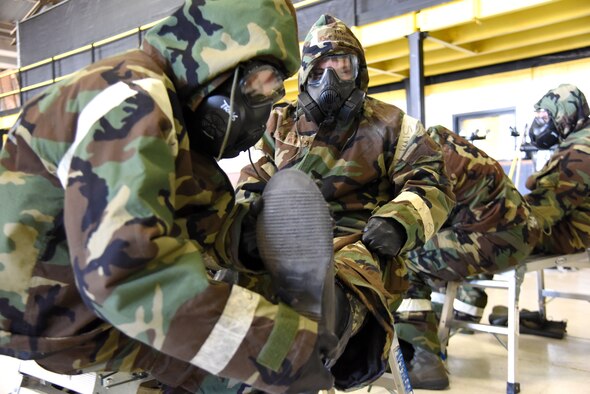 Airman 1st Class Jerrod Nichols, 4th Equipment Maintenance Squadron aircraft structural maintenance journeyman, removes an overboot from Tech. Sgt. Richard Zerr, 4th Civil Engineer Squadron noncommissioned officer in charge of electrical systems, Jan. 29, 2016, at Seymour Johnson Air Force Base, N.C. Airmen from around the base participated in an "ability to survive and operate rodeo" to kick off exercise Coronet Warrior 16-01. (U.S. Air Force photo/Staff Sgt. Chuck Broadway) 