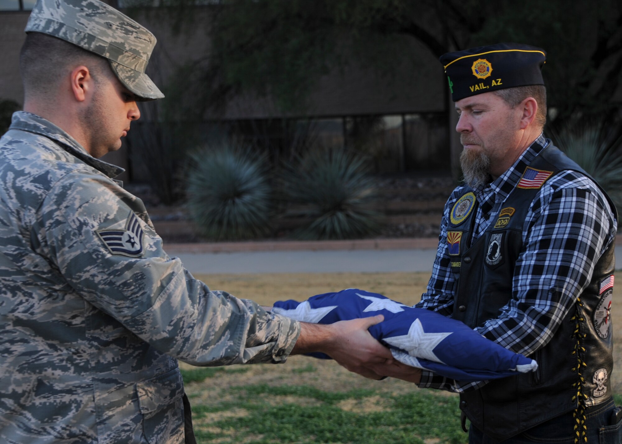 U.S. Air Force Staff Sgt. Steven Sinatra, 355th Medical Support Squadron diagnostic imaging technologist, hands off the American flag to retired U.S. Army Maj. William Garris, McCulloch-Wagner American Legion Post 109 commander, during a retreat ceremony at Davis-Monthan Air Force Base, Ariz., Jan. 28, 2016. Veterans from the American Legion received the American flag and will work with a local Boy Scout troop to conduct the flag retirement ceremony at a later date. (U.S. Air Force photo by Airman Basic Nathan H. Barbour/Released)