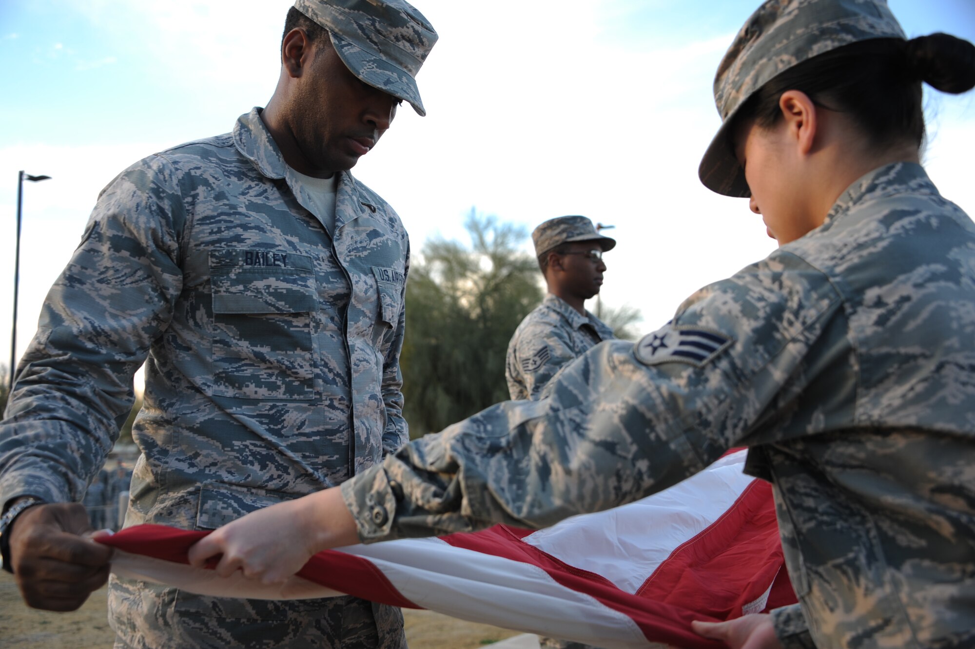 U.S. Air Force Airman First Class Durelle Bailey, 355th Medical Support Squadron, Senior Airman Zenny Dinh 355th Aerospace Medicine Squadron fold the American flag while Staff Sgt. Tarell Walker holds it firmly during a retreat ceremony at Davis-Monthan Air Force Base, Ariz., Jan. 28, 2016. The American flag flying outside the 355th Fighter Wing building was taken down ceremoniously and handed off to the McCulloch-Wagner American Legion post 109 to be retired. (U.S. Air Force photo by Airman Basic Nathan H. Barbour/Released)
