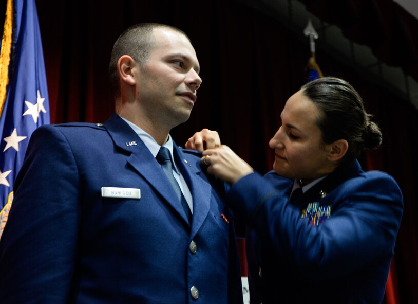 2nd Lt. Alexandru Bunescu, Basic Officer Training Course cadet, has his rank pinned on by his wife, 2nd Lt. Cristina Bunescu, BOT Course cadet, during their graduation ceremony at the Jeanne M. Holm Center for Officer Accessions and Citizen Development on Maxwell Air Force Base, Ala., Dec. 17, 2015. During the nine-week program, the couple learned the basics of leadership and military management as well as obtaining skills to become a military officer. 