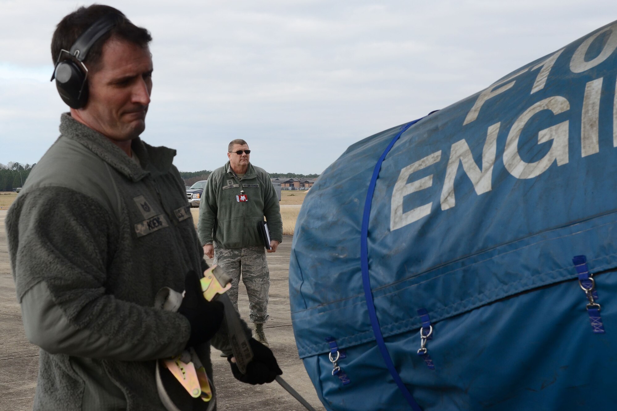 U.S. Air Force Tech. Sgt. Bennett Koenig, assigned to the 169th Logistics Readiness Squadron, loads cargo into a Georgia Air National Guard C-130H3 Hercules on the flight line at McEntire Joint National Guard Base, S.C., Jan. 21, 2016 as Chief Master Sgt. Lanny Cobb (background), a Wing Inspection Team member assigned to the 169th Fighter Wing, evaluates the equipment loading and deployment processes. The evaluation is part of a mid-point inspection that is a mandatory measure of the Air Force Inspection System. (U.S. Air National Guard photo by Senior Airman Ashleigh Pavelek)