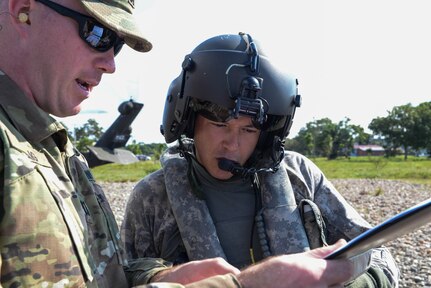 U.S. Army Capt. Cameron Craig, Joint Task Force-Bravo tactical team officer in charge, shows a flight itinerary to Sgt. Ruben Ramos, 1-228th Aviation Regiment UH-60 Blackhawk helicopter crew chief in the Gracias a Dios Department (state), Honduras, Jan. 13, 2016. The Army supported the Honduran troop movement, Operation CARAVANA, by transporting Honduran troops to various points the department. (U.S. Air Force photo by Senior Airman Westin Warburton/Released)
