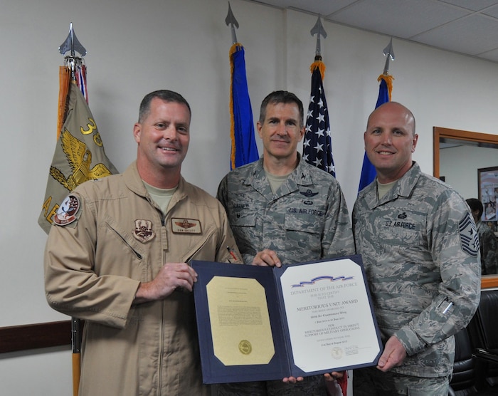 Brig. Gen. Daniel Orcutt, 380th Air Expeditionary Wing commander, Col. Johnny Barnes, 380 AEW vice commander, and Chief Master Sgt. Charles Mills, 380 AEW command chief, left to right respectively, pose for a group photo after the 380th is awarded the Meritorious Unit Award during a ceremony at an undisclosed location in Southwest Asia, Jan. 18, 2016. The award recognizes Air Force active duty, Reserve and Guard units for exceptionally meritorious conduct in the performance of outstanding achievement or service in direct support of combat operations for at least 90 continuous days during the period of military operations against an armed enemy of the U.S. on or after Sept. 11, 2001. (U.S. Air Force photo by Staff Sgt. Kentavist P. Brackin/Released)