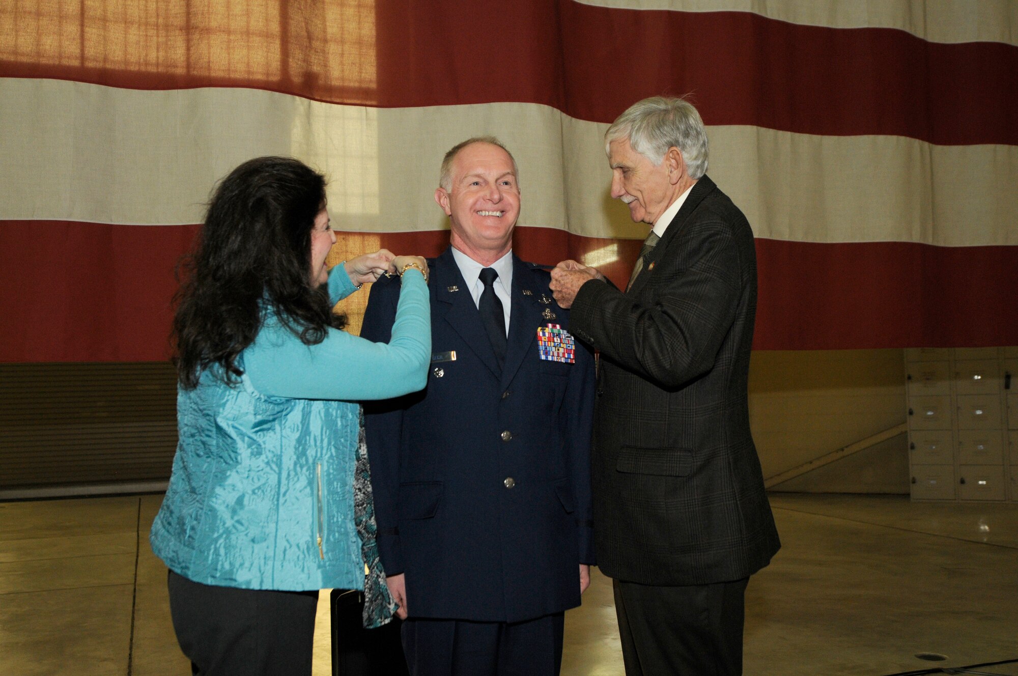 U.S. Air Force Lt. Col. Allan R. Cecil (center), deputy commander of the 145th Maintenance Group, has the rank of colonel pinned onto his uniform by his spouse and retired Brig. Gen. Fisk Outwater during a ceremony held in his honor at the North Carolina Air National Guard Base, Charlotte Douglas International Airport, Jan. 9, 2016. In 1977, at the rank of Master Sergeant, Cecil was commissioned as a weather officer. (U.S. Air National Guard photo by Staff Sgt. Julianne M. Showalter/Released)