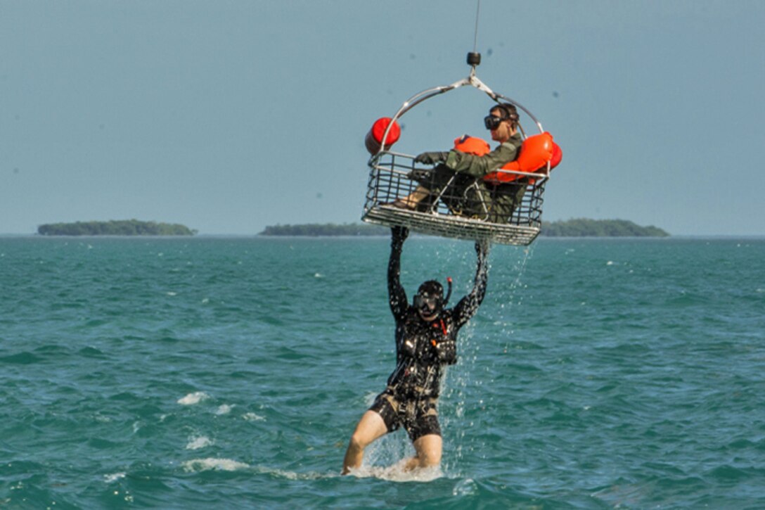 An airman sits in a recovery basket as a sailor hangs onto it during Operation Jesse Relief, a joint search-and-rescue exercise, off the coast of Key West, Fla., Jan. 26, 2016. Missouri Air National Guard photo by Senior Airman Sheldon Thompson