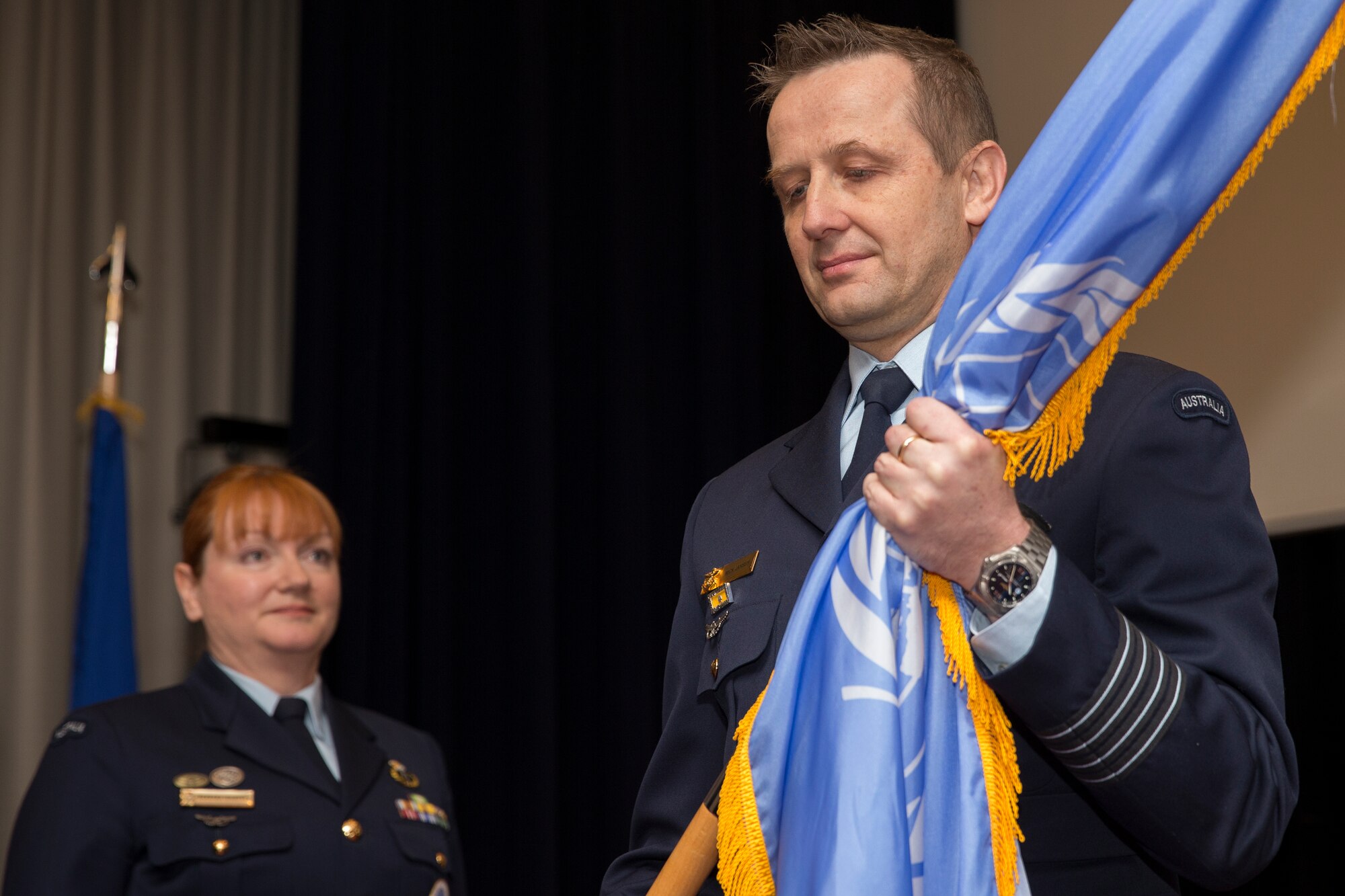 Royal Australian Air Force Group Captain Michael Jansen, incoming United Nations Command (Rear) commander, receives the guidon during a change of command ceremony at Yokota Air Base, Japan, Jan. 26, 2016. The UNC (Rear) has historically been commanded by a U.S. Army Colonel however since 2010 the command has been filled by an Australian Air Force officer with this change of command assigning the fourth successive Australian commander. (U.S. Air Force photo by Osakabe Yasuo/Released)