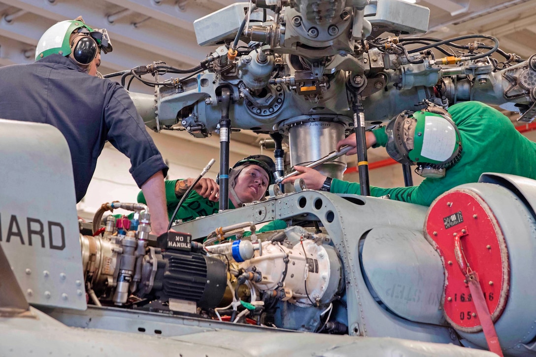 Sailors maintain an MH-60S Seahawk helicopter in the hangar bay of the amphibious assault ship USS Bonhomme Richard in the Pacific Ocean, Jan. 29, 2016.The assault ship is operating in the U.S. 7th Fleet area of operation. Navy photo by Seaman William Sykes