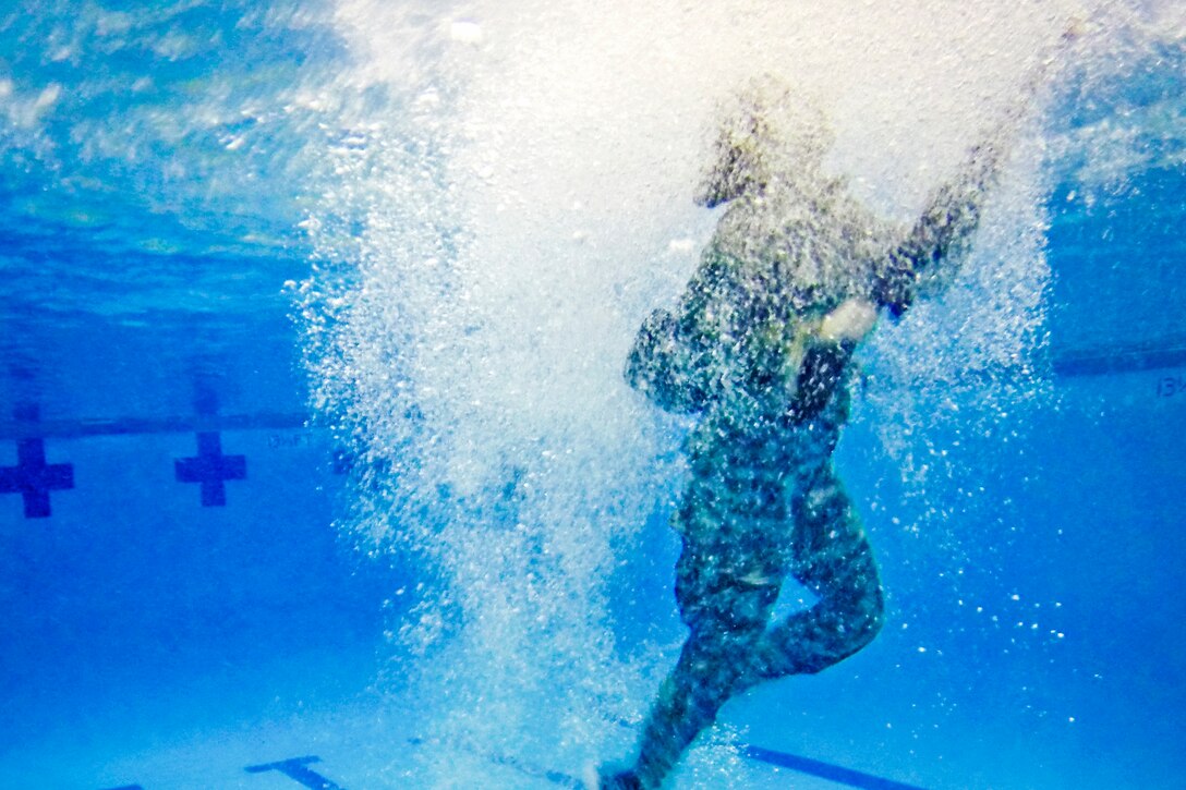 Army ROTC cadet Kerry Carter surfaces after plunging blindfolded into a pool during a combat water survival test at Clemson University, S.C., Jan. 28, 2016. Blindfolded participants carrying an M16 must drop into the water and return to the pool's side with their weapon in hand. Army photo by Staff Sgt. Ken Scar