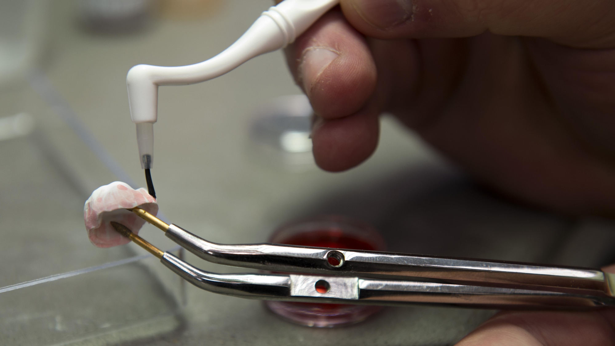 Staff Sgt. Samuel Brown, 86th Dental Squadron certified dental technician, paints a zirconia crown June 30, 2016, at Ramstein Air Base, Germany. Brown painted the crown to look more natural and so that it won’t stand out against regular teeth. (U.S. Air Force photo/Airman 1st Class Tryphena Mayhugh)