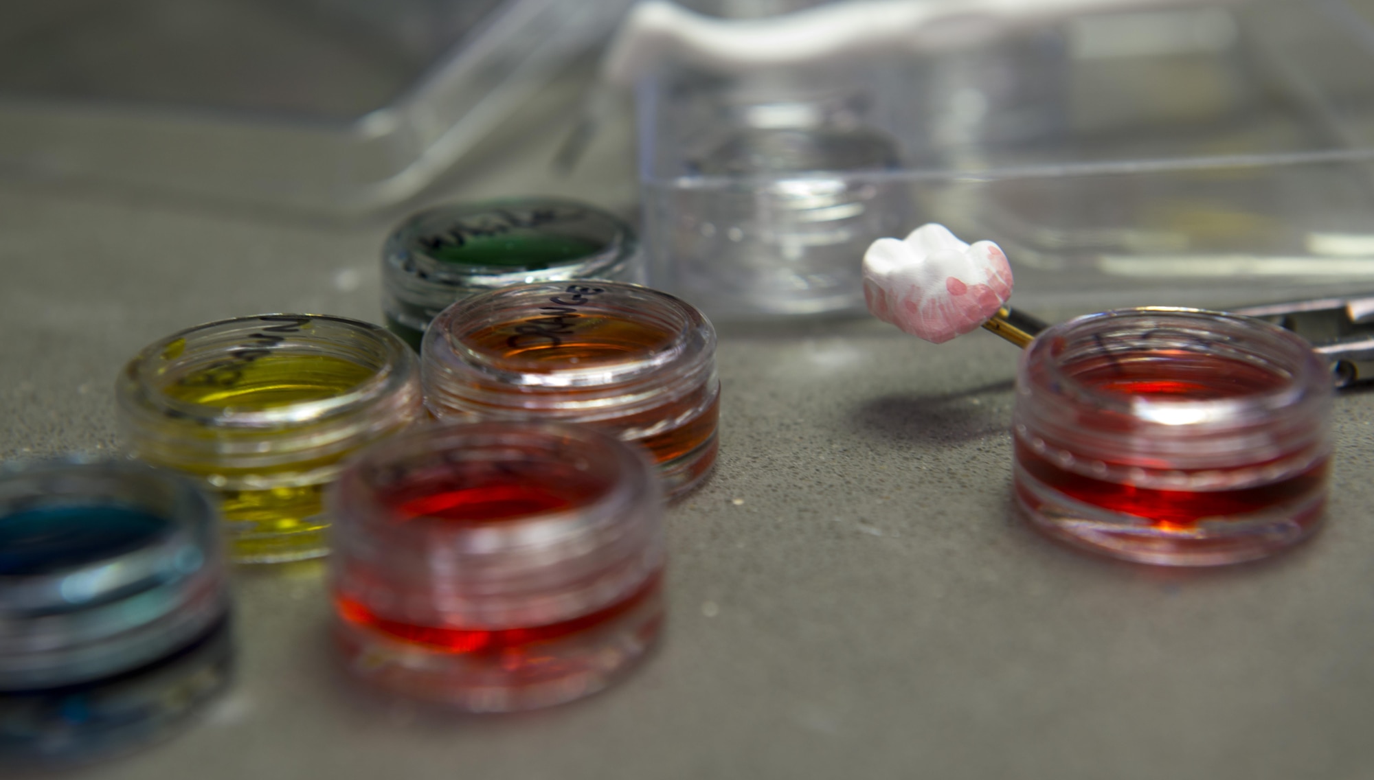 Paints and dyes lay next to a zirconia crown on a table at the 86th Dental Squadron dental lab June 30, 2016, at Ramstein Air Base, Germany. Dental lab technicians paint and die crowns so they blend in with regular teeth. (U.S. Air Force photo/Airman 1st Class Tryphena Mayhugh)