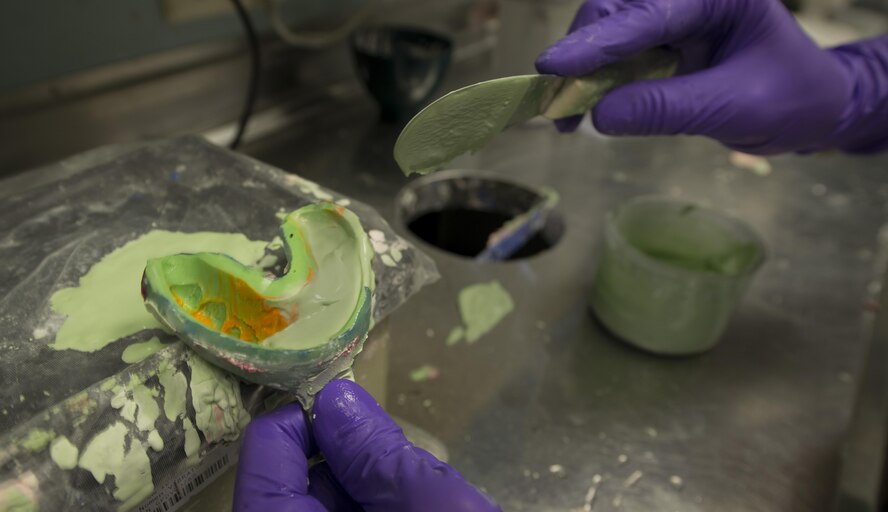 Senior Airman Tanner Scott, 86th Dental Squadron dental lab technician, fills a mold of teeth with plaster June 30, 2016, at Ramstein Air Base, Germany. Once the mold dries, dental lab technicians will be able to use it to create sports guards, hard night guards or retainers for the customer. (U.S. Air Force photo/Airman 1st Class Tryphena Mayhugh)