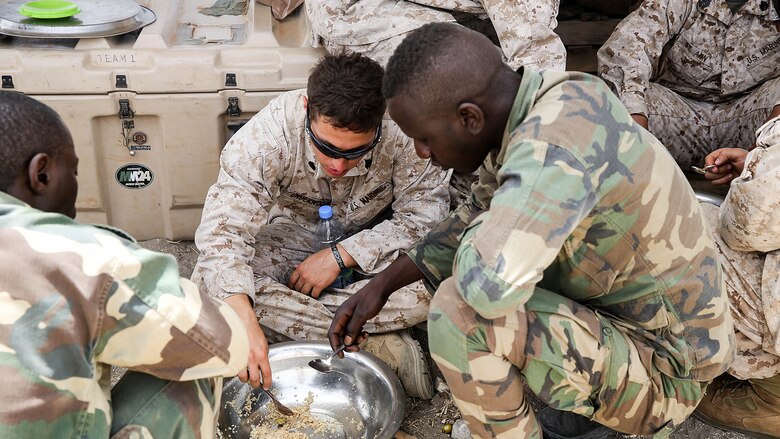 Sgt Ryan Underwood, a rifleman with Special Purpose Marine Air-Ground Task Force Crisis Response-Africa, shares lunch with the Compagnie Fusilier de Marin Commando in Thies, Senegal, June 22 2016. Marines and the COFUMACO conducted a three-week training exercise that included advanced combat firing techniques, a machine gun range and a live-fire platoon attack range. 