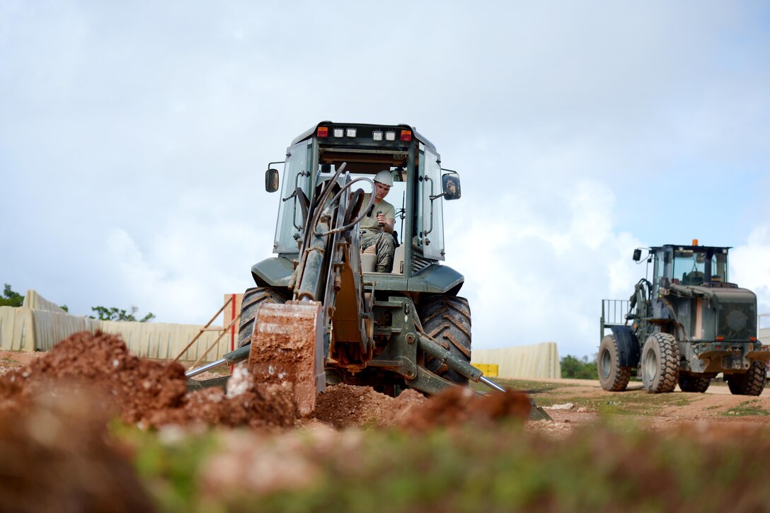 Senior Airman Peter Berg operates a backhoe to dig a trench to help drain water away from a construction site at Andersen Air Force Base, Guam, June 21, 2016. Berg is assigned to the New Hampshire Air National Guard’s 157th Civil Engineering Squadron. Air National Guard photo by Tech. Sgt. Aaron Vezeau