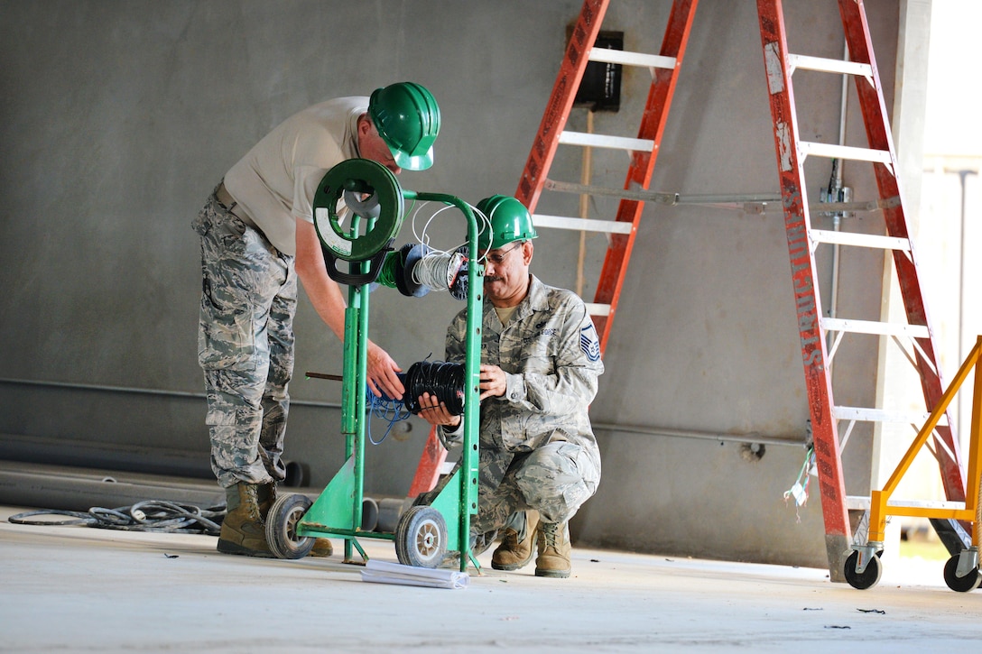 Air Force Master Sgt. Cesar Rivera, right, and Tech. Sgt. Victor Union prepare to pull electrical wiring to be used during construction of the Commando Warrior Field Training Facility at Andersen Air Force Base, Guam, June 22, 2016. Rivera and Union are electricians assigned to the New Hampshire Air National Guard’s 157th Civil Engineering Squadron. Air National Guard photo by Tech. Sgt. Aaron Vezeau