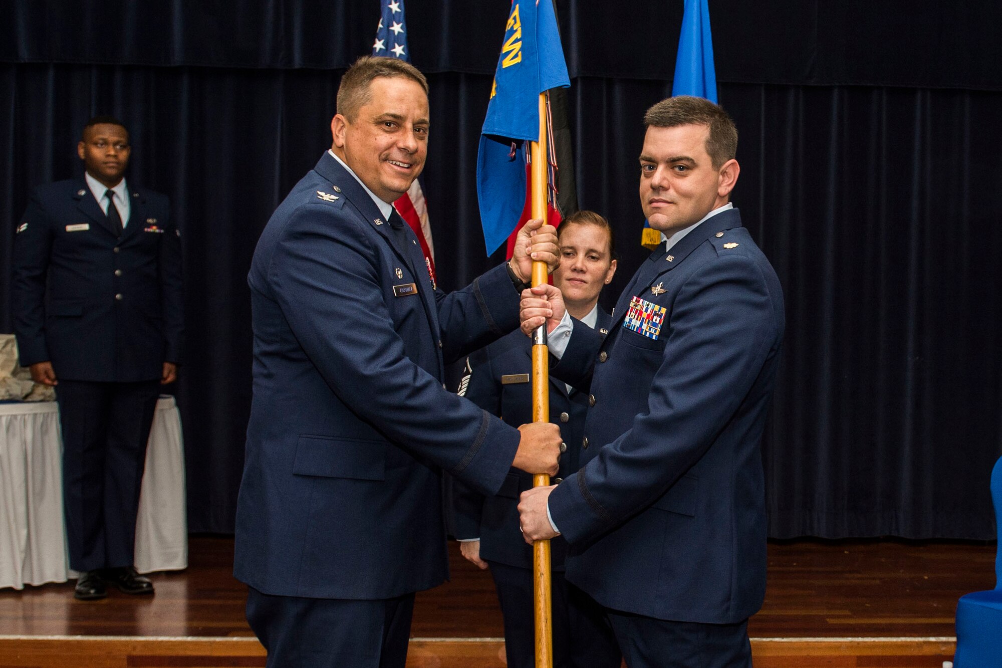 U.S. Air Force Col. Steven Zubowicz, 52nd Mission Support Group commander, left, passes the 52nd Communications Squadron guidon to U.S. Air Force Maj. Christopher Waddell, 52nd CS commander, during the 52nd CS change of command ceremony in the Club Eifel Ballroom at Spangdahlem Air Base, Germany, July 1, 2016. The passing of the guidon is military tradition when exchanging command. (U.S. Air Force photo by Senior Airman Luke Kitterman/Released)