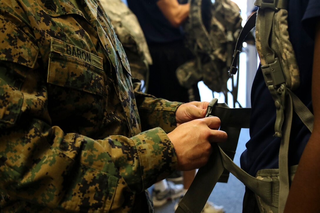 U.S. Marine Corps Sgt. Jacob T. Baron, a recruiter with Recruiting Substation Carlisle, shows a poolee how to properly use and adjust a weighted pack at the recruiting station prior to a four mile hike in Carlisle, Penn., on Saturday, June 18, 2016. The purpose of the hike was to provide training as well as mentorship to female poolee by teaching them the proper way to pack and carry heavy loads during hikes. (U.S. Marine Corps photo by Sgt. Anne K. Henry/Released) 