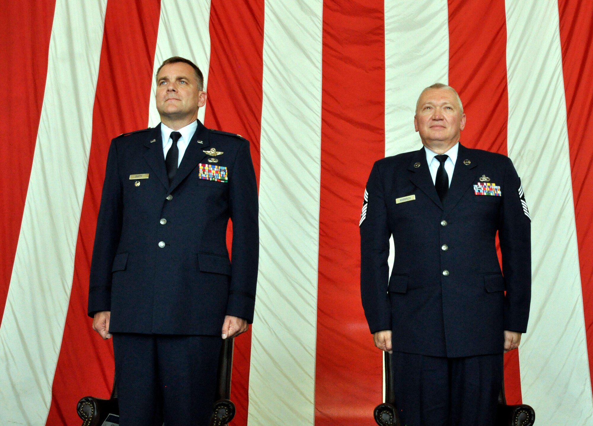 Chief Master Sgt,. Kevin Warbrick, right, command chief, 514th AIr Mobility Wing and Col. Dennis Duffy, left, vice commander 514th AMW, stand ready as the National Anthem is sung by the chief's wife and two daughters. Warbrick officially retires today after 33 years of military service. His retirement ceremony was held here Sunday.   